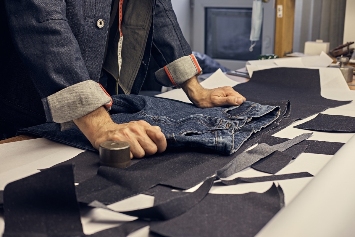 Sastre tomando medidas sobre denim en el taller